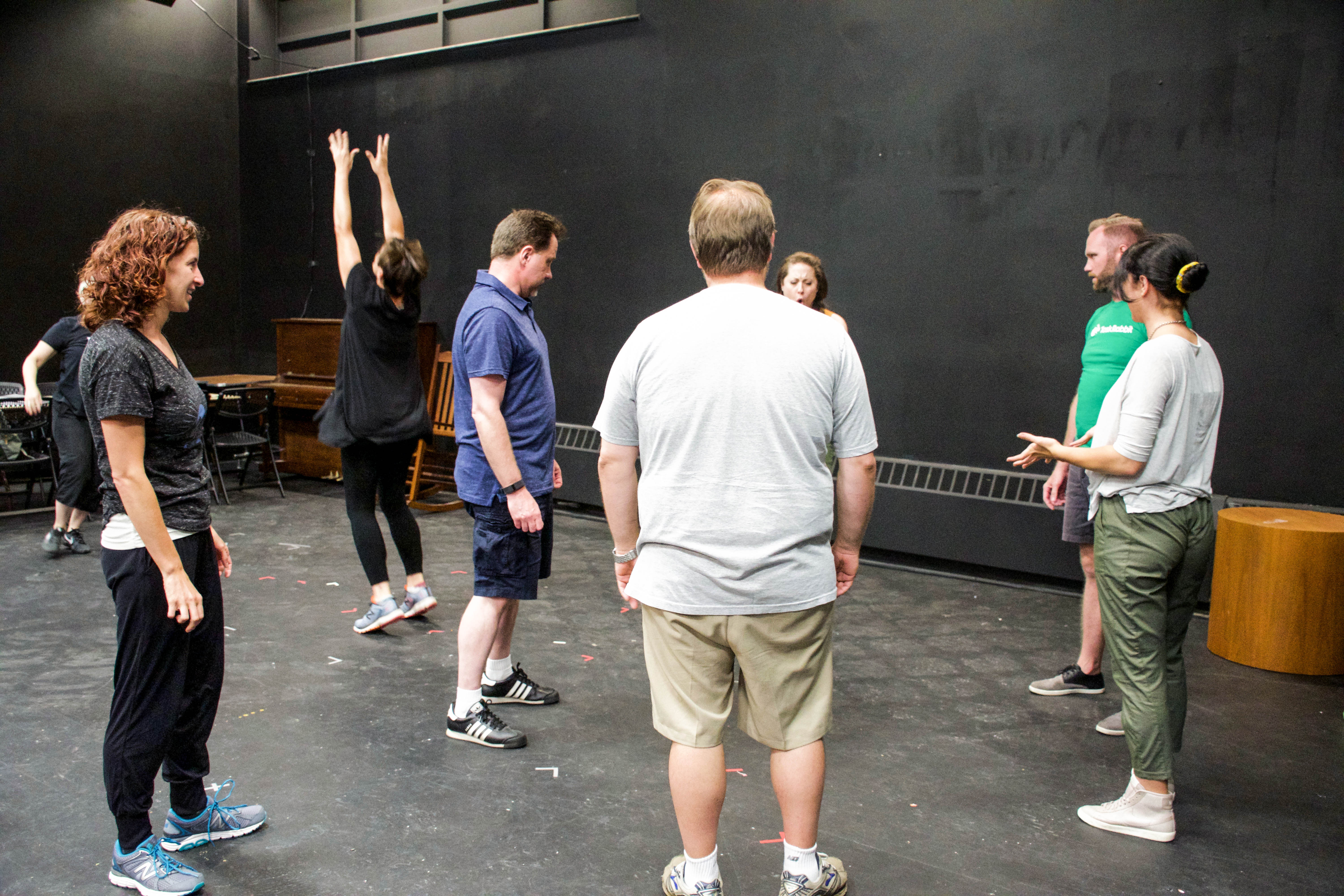 Actors in a rehearsal room standing in a circle working on movement