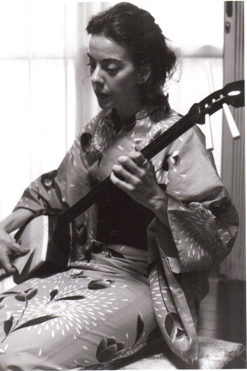 Janet Pocorobba plays the shamisen in a traditional Japanese dress. The shamisen is a three-stringed instrument with a long neck like a guitar.