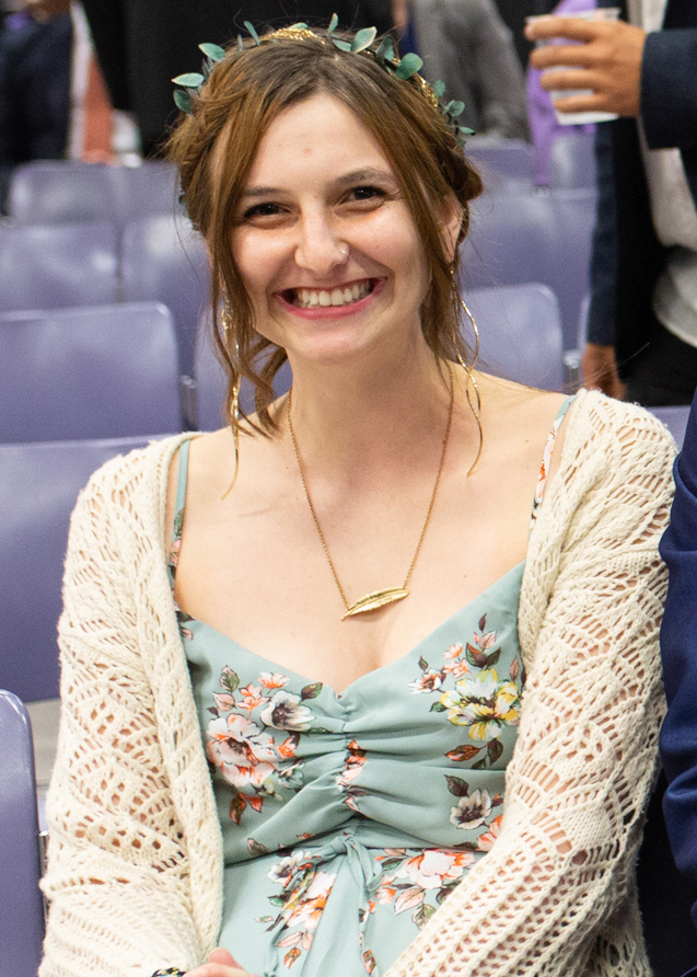 Katya Zinn seated wearing a floral dress and lace cardigan