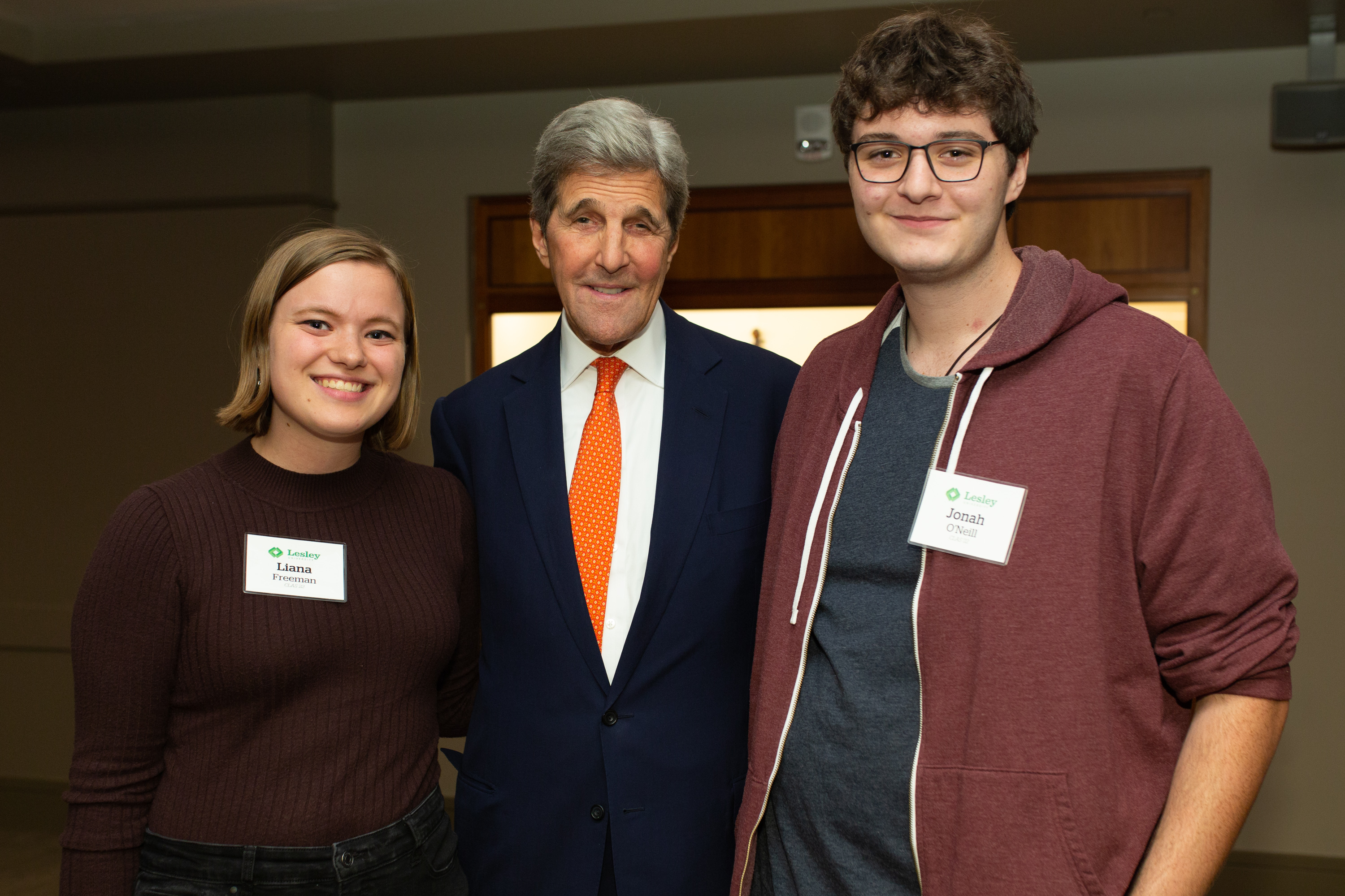 Students Liana Freeman and Jonah O’Neill stand on either side of John Kerry posing for a photo