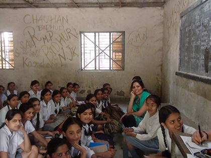 a room full of young students sitting on the floor facing the chalkboard