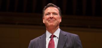 James Comey smiles while standing on the Symphony Hall stage