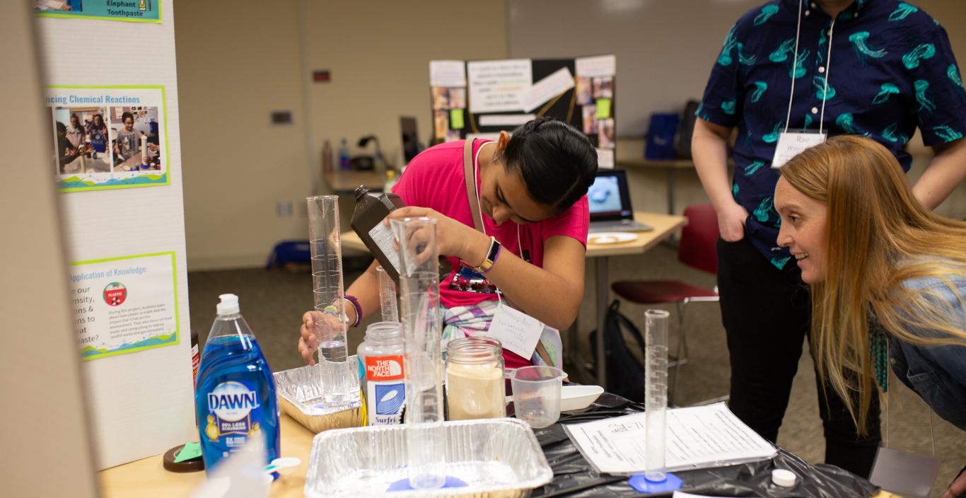 Teacher Lindsay Tosches looks on as a student pours liquid into a beaker.