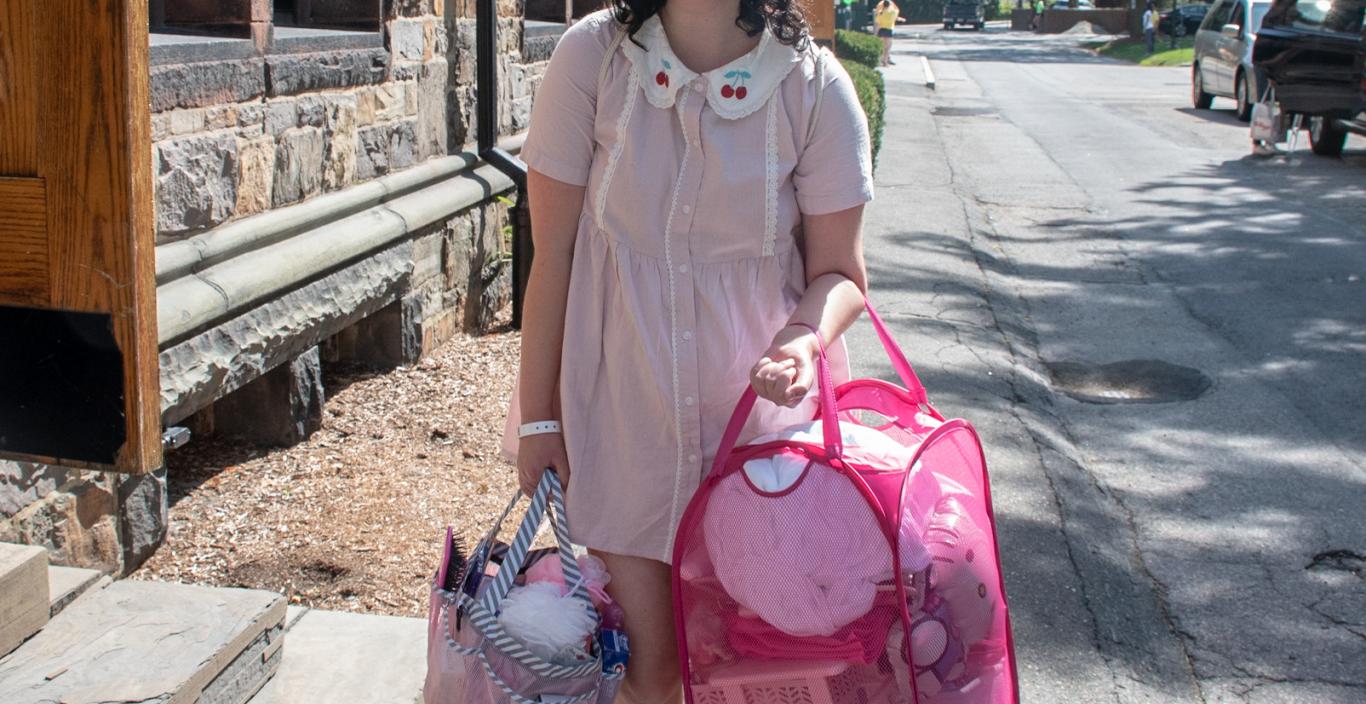 A girl dressed all in pink carries her pink accessories on move-in day.