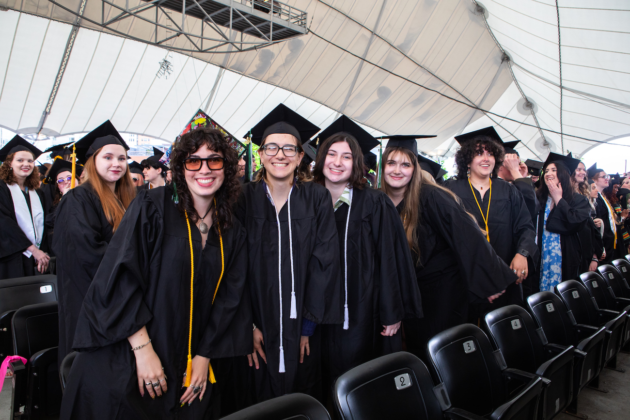 Graduates in black caps and gowns smiling at camera