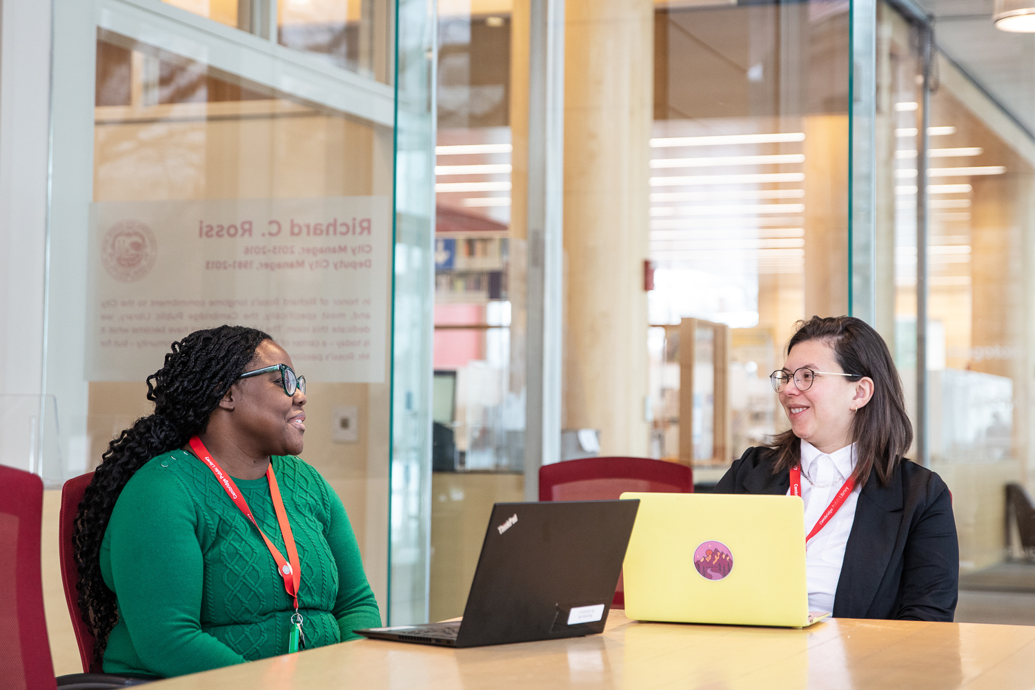 Emma Henson and Marie Mathieu sit at a table in front of their laptops.