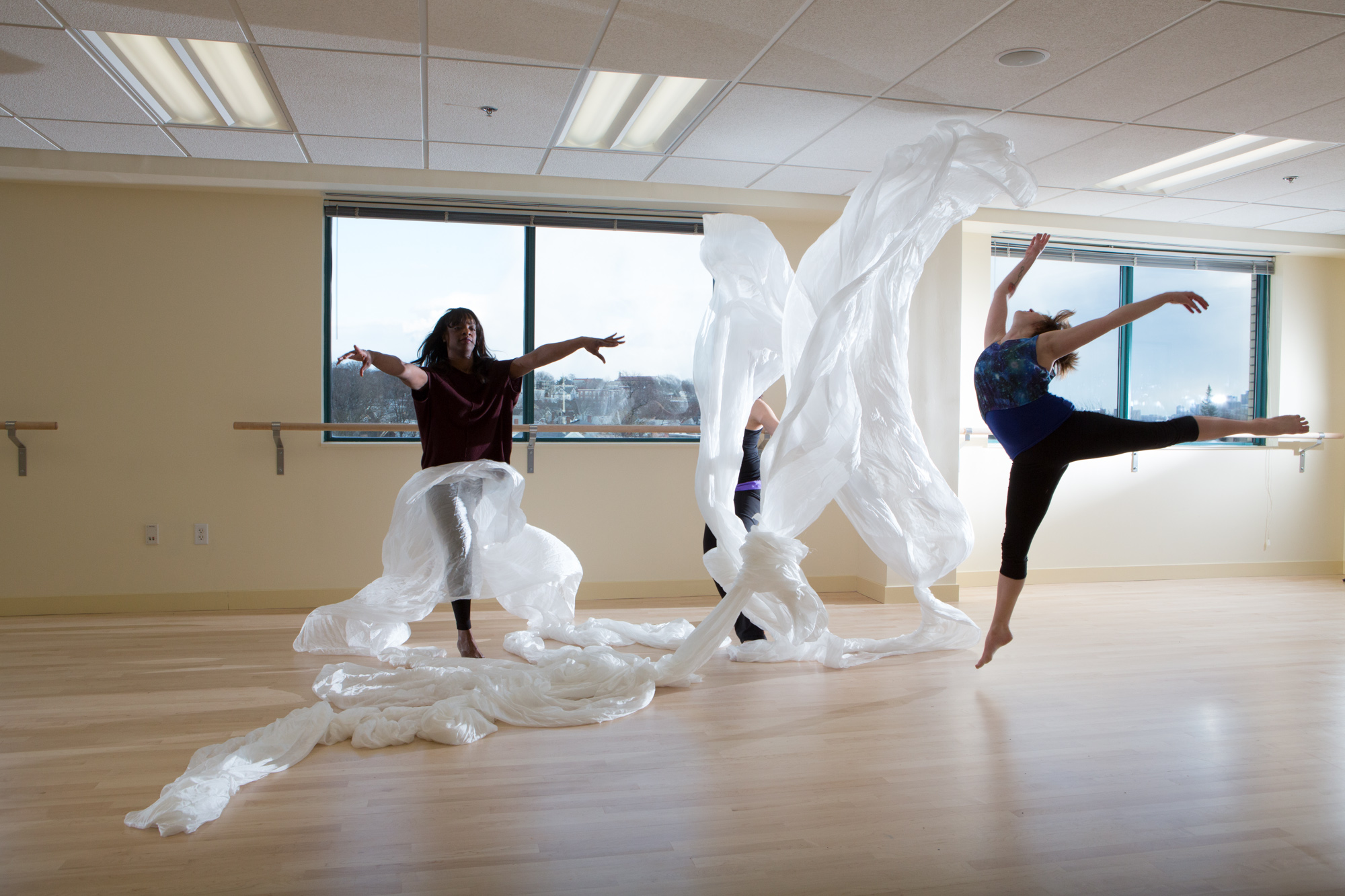 Movement Therapy students, dancing with white sheets in a well-lit dance studio