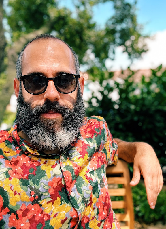 Nick sitting outside wearing sunglasses and colorful shirt