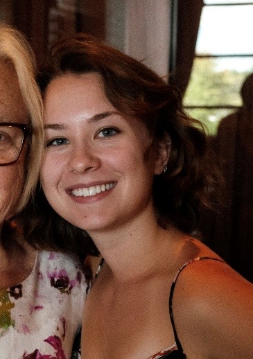 Individual stands next to another woman smiling at the camera