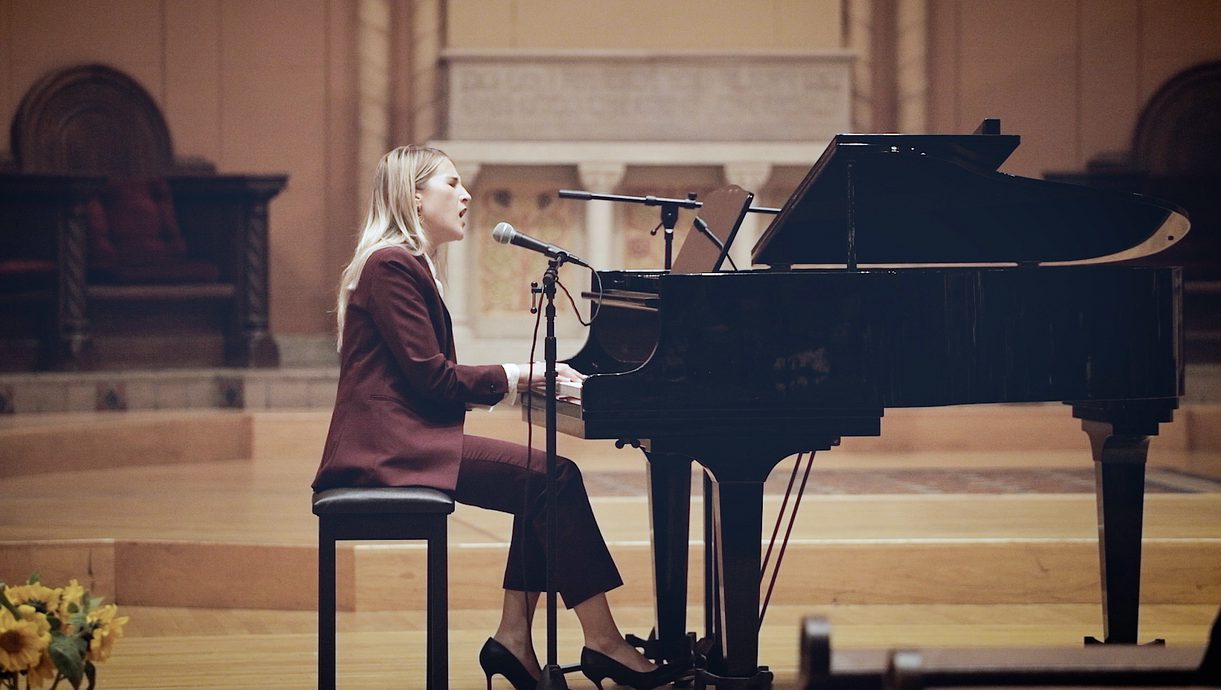 Nathalie Robelot Timtchenko plays a piano and sings into a microphone