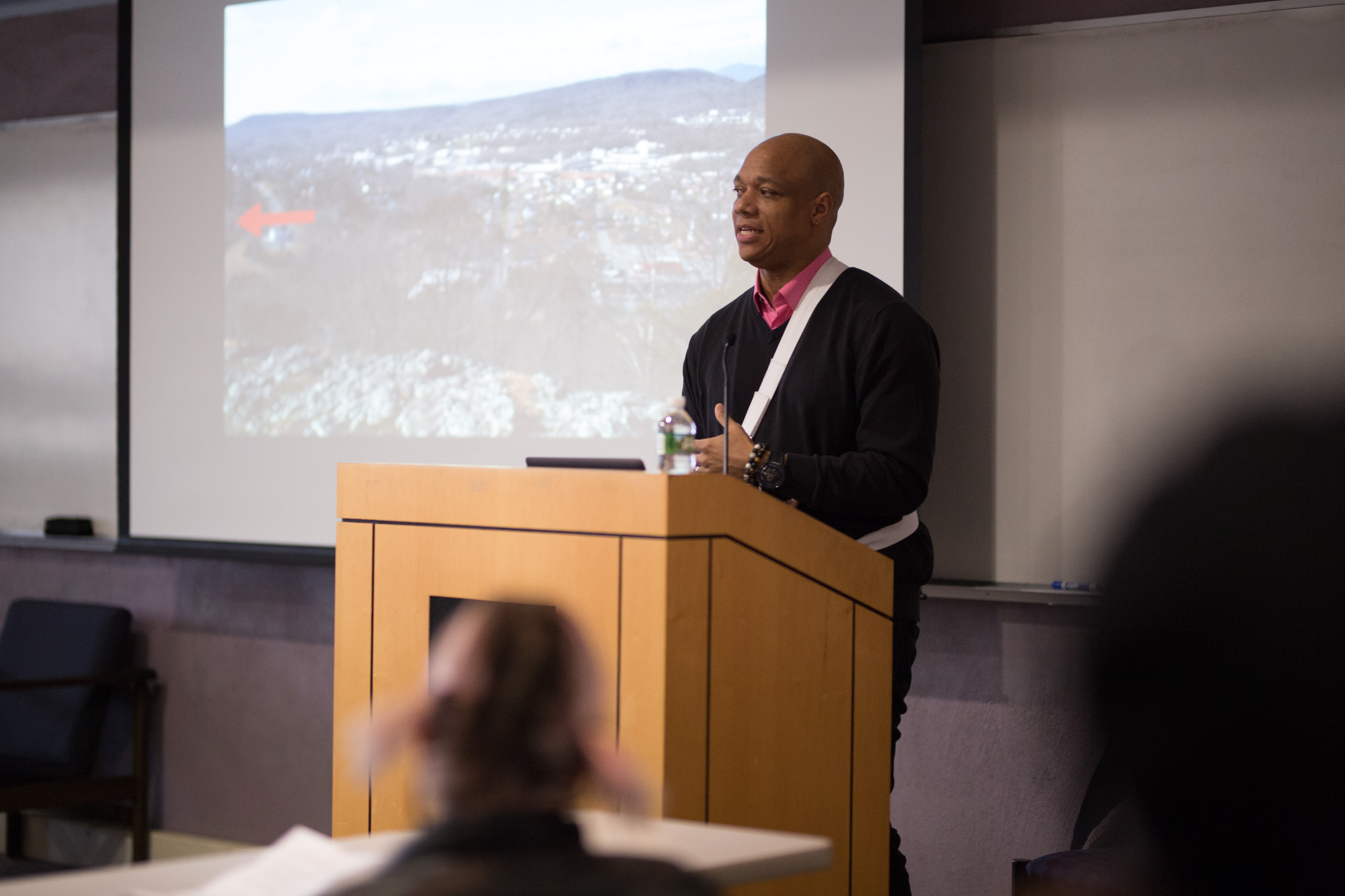 Joel Christian Gill is pictured at a podium with a photo slide in the background