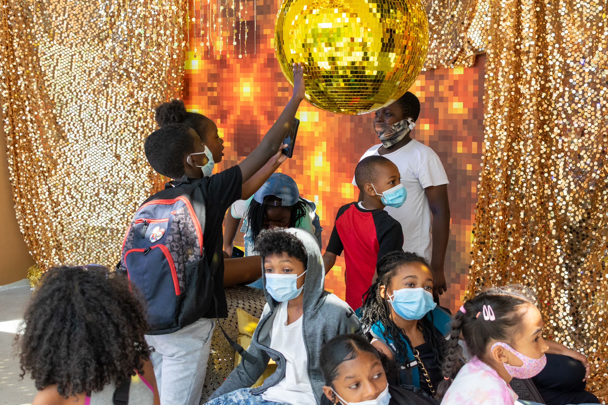 Kids with masks in a room with gold walls and a disco ball
