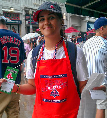 Ashley Delgado wearing a red apron and Red Sox hat at Fenway.