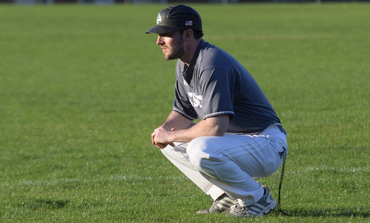 Head Coach Billy Cather crouches on the field as he watches the game.