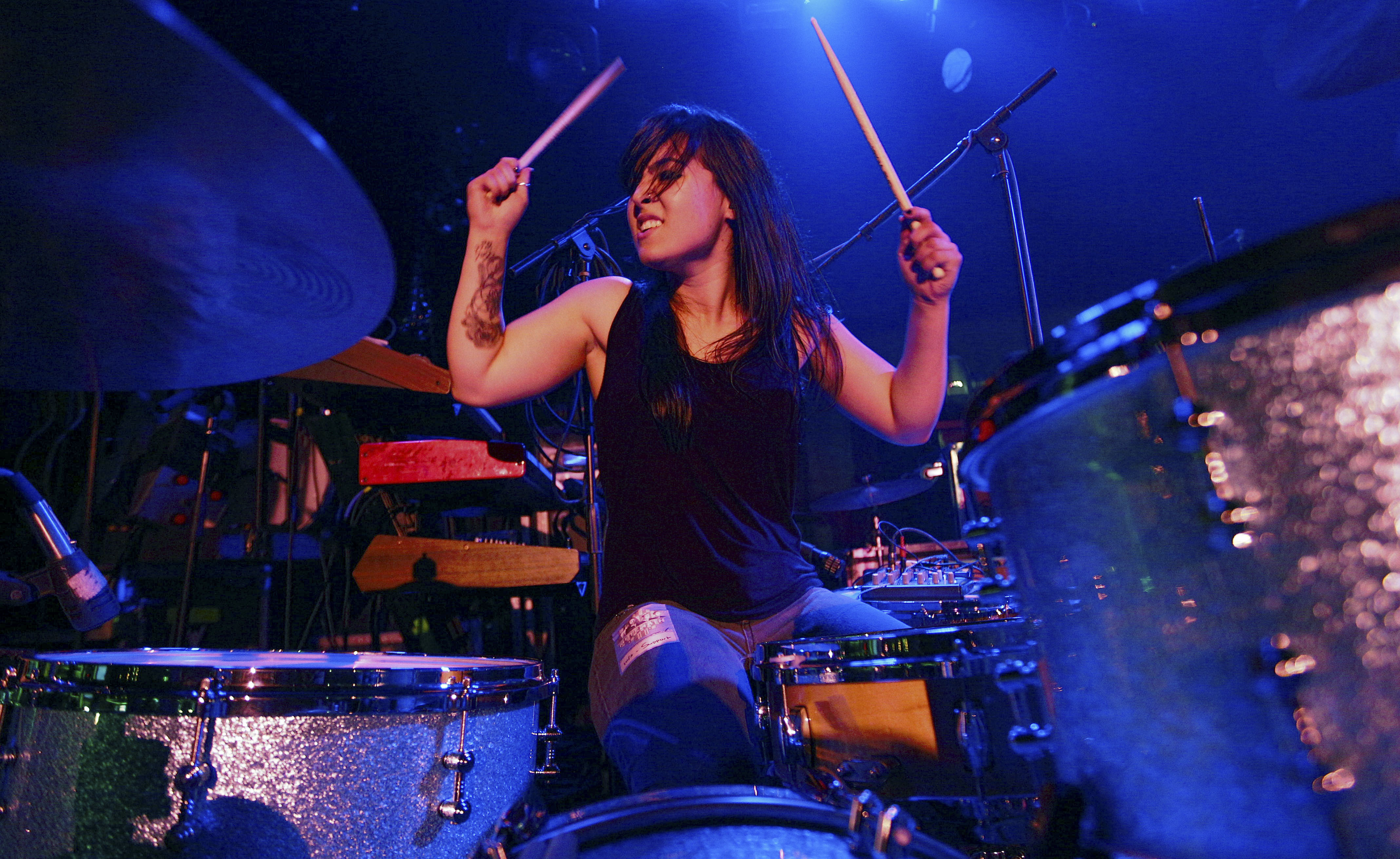Lesley alum Caitlin Kalafus at her drum set, playing the drums on stage.