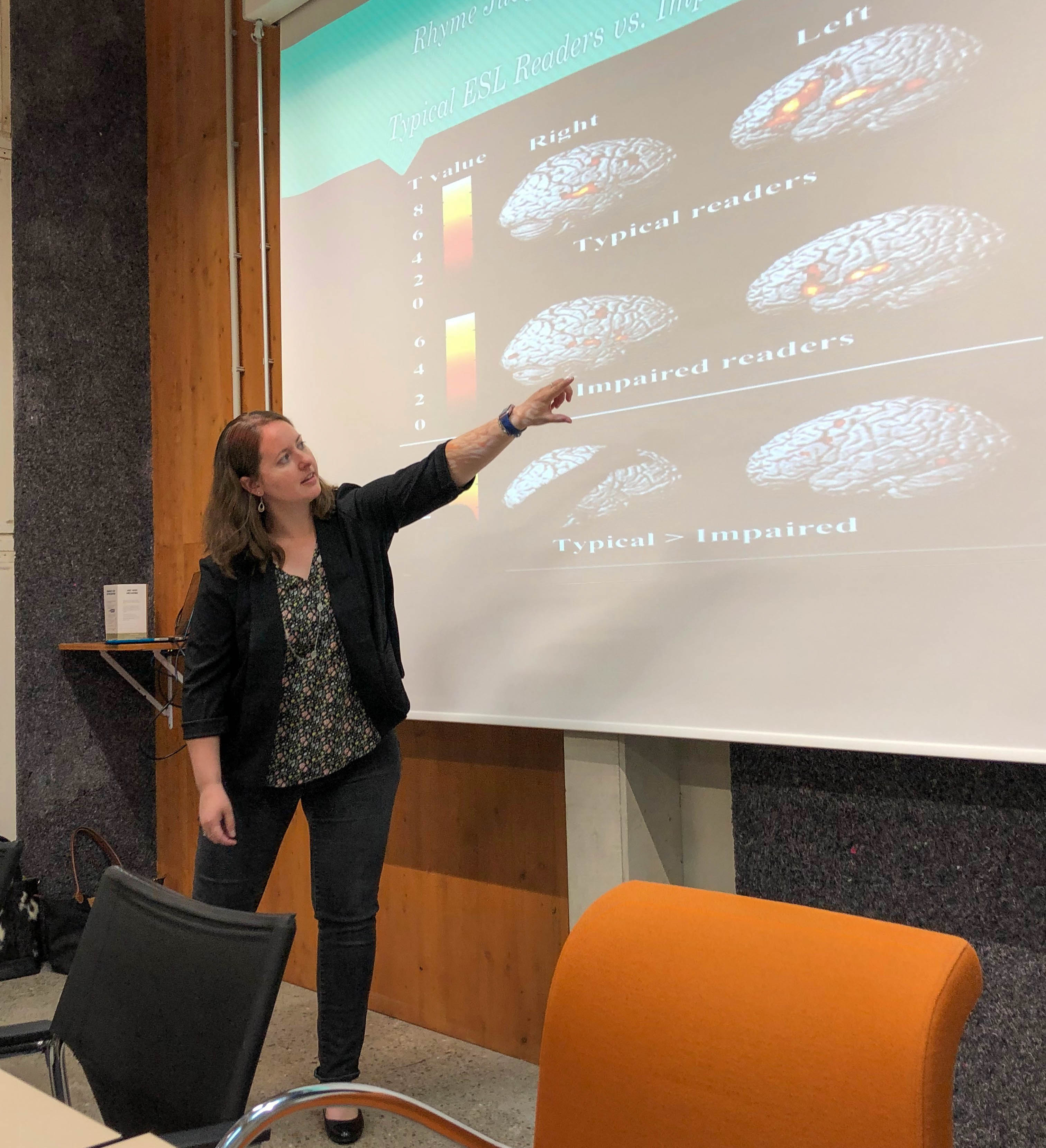 Carolyn Peterson presents her research, pointing to a presentation on a screen with images of brains