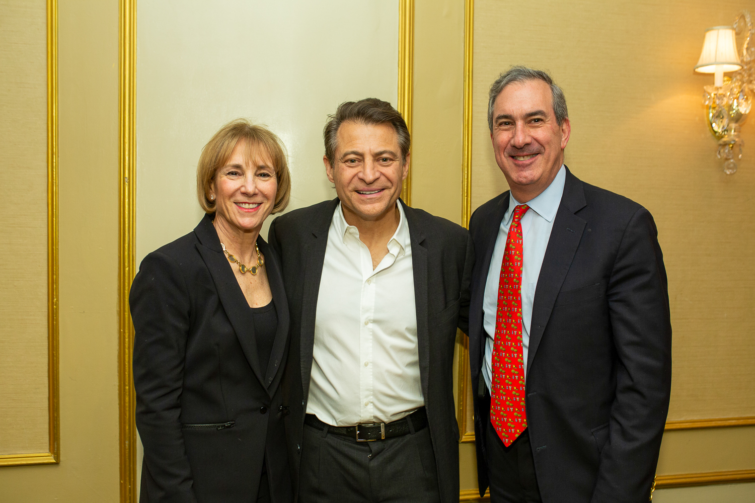 A man and woman stand on either side of Peter Diamandis