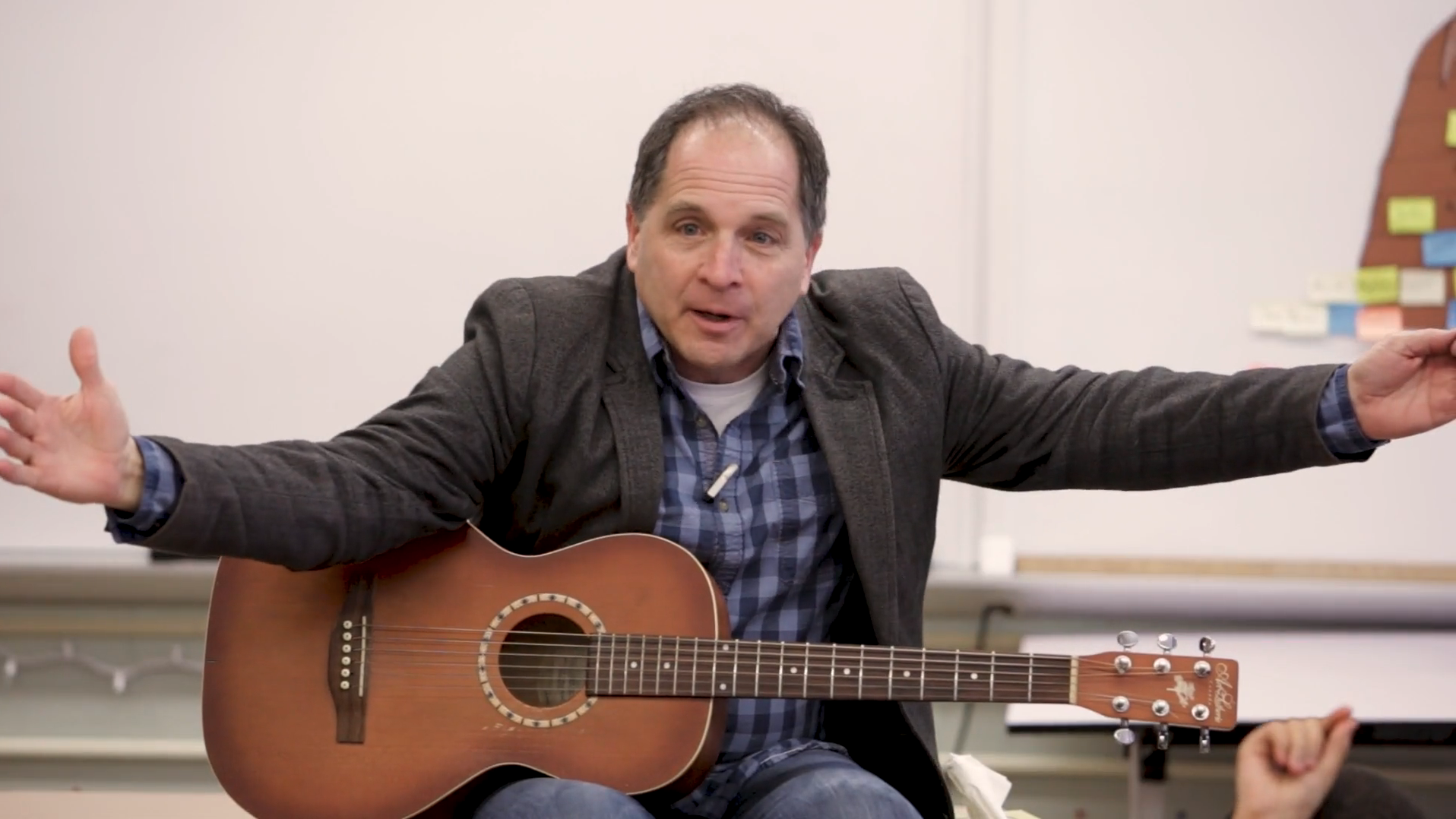 David Levine '84 gestures while holding his guitar