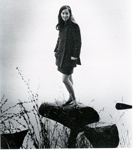 Debbie Schwartz poses for a photo on a rock surrounded by water.