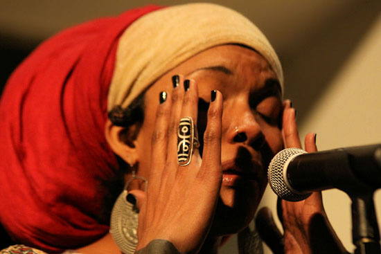 Dominique Cristina with hands to her temple and speaking into a microphone