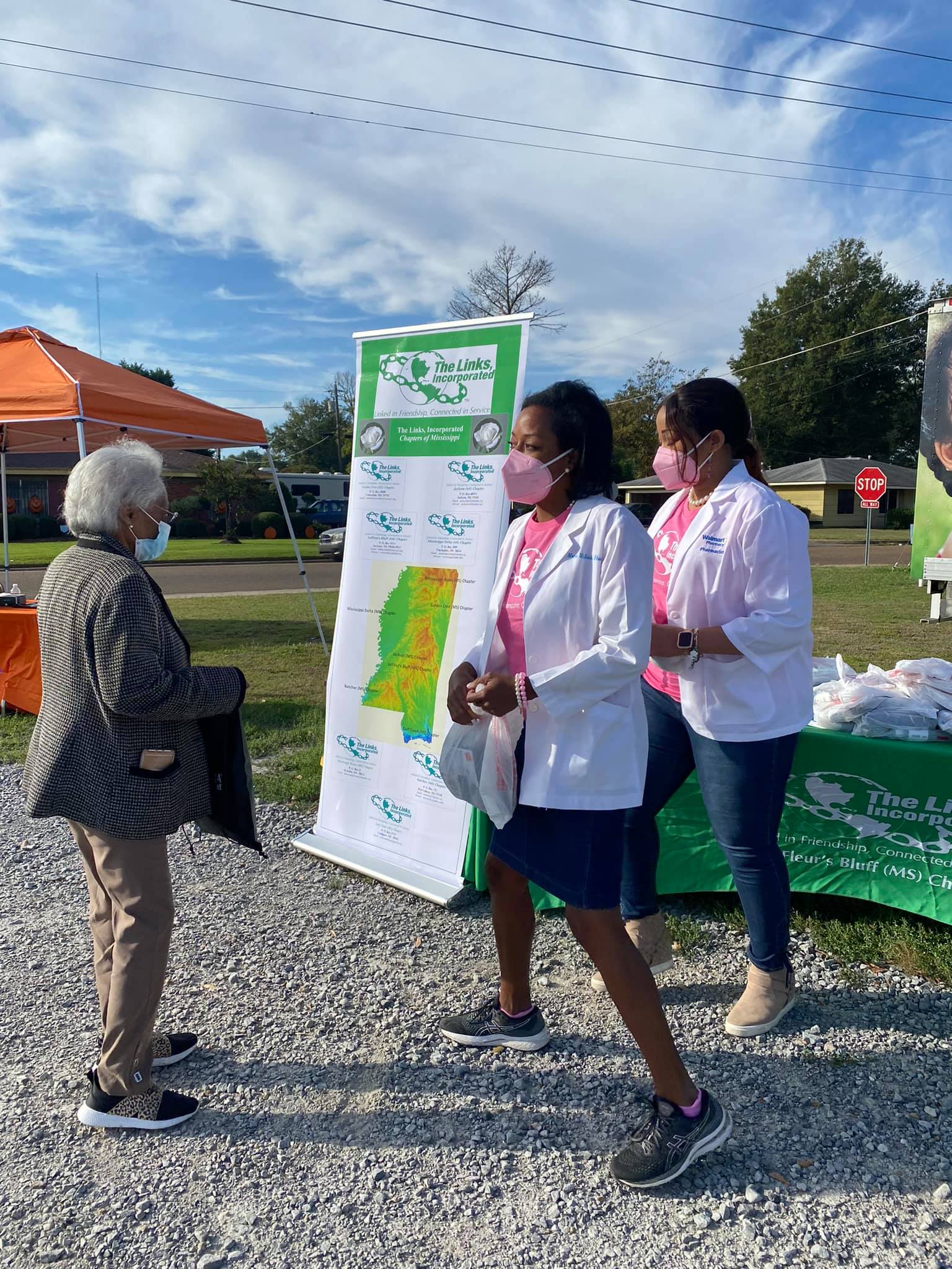 Two women in medical coats at an outdoor event