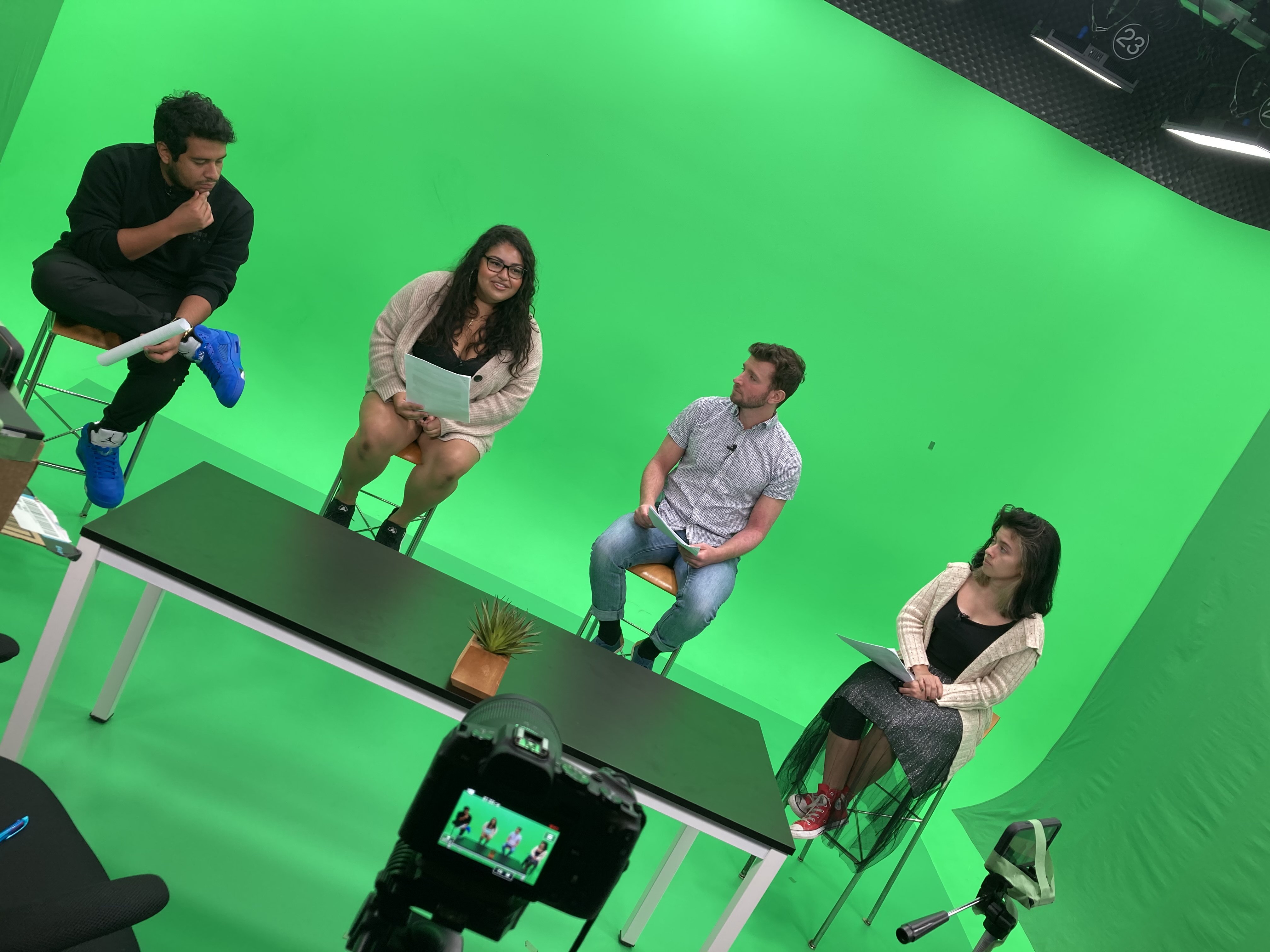 People sitting on stools in front of a green screen