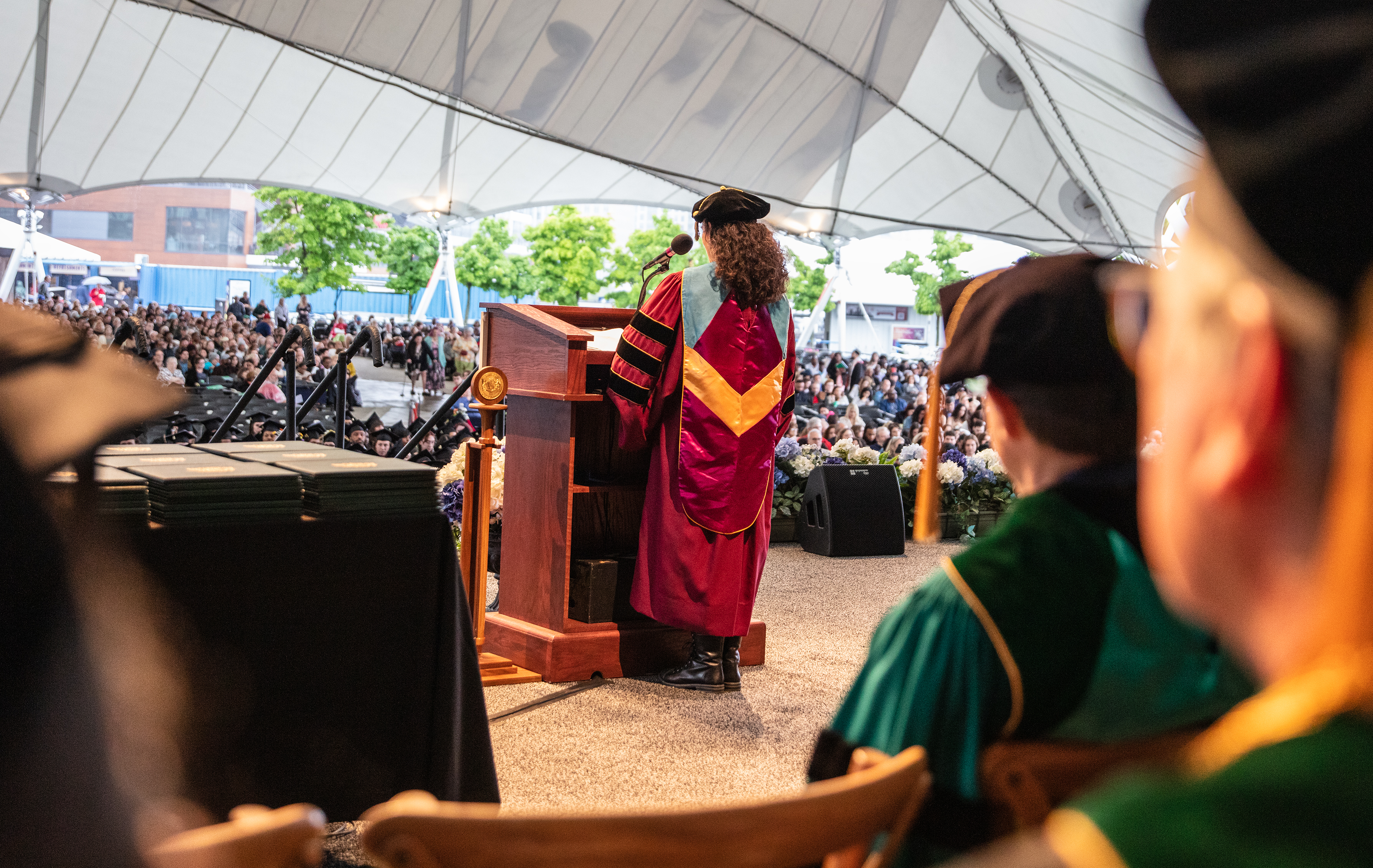 lisa fiore in academic regalia speaking for graduates in pavilion