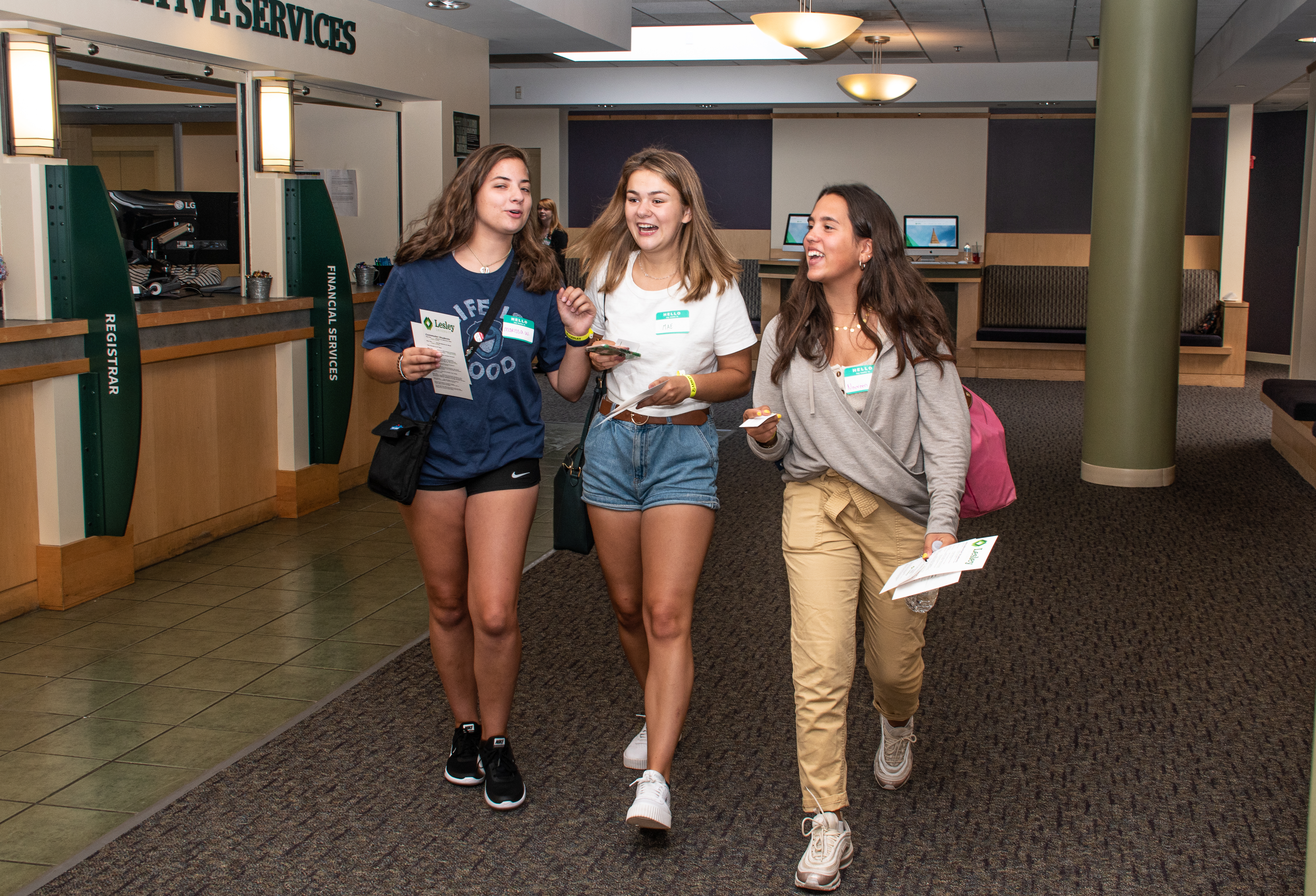 Three students smiling at each other as they walk through University Hall