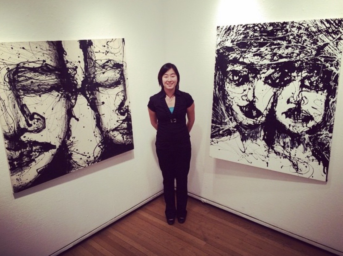 Noel King in an art galley flanked by large black and white portraits