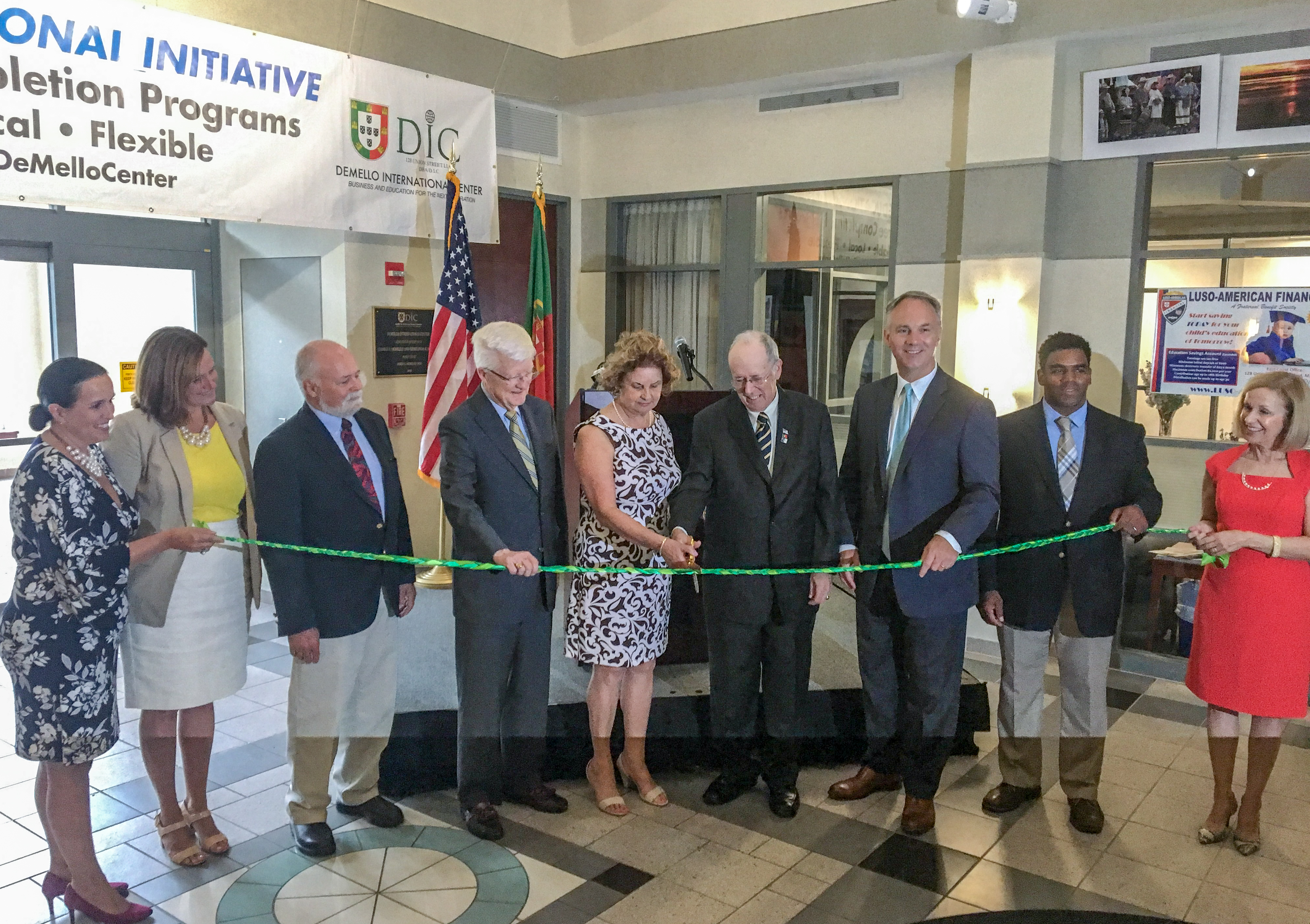 Leaders from Lesley and the Rising Tide partners stand in a line behind long ribbon being cut in the DeMello International Center.