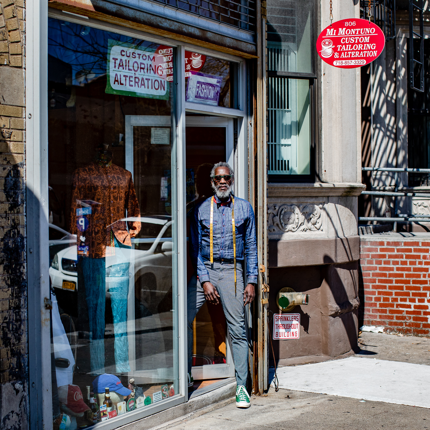 A man stands in the doorway of his tailor shop in Brooklyn