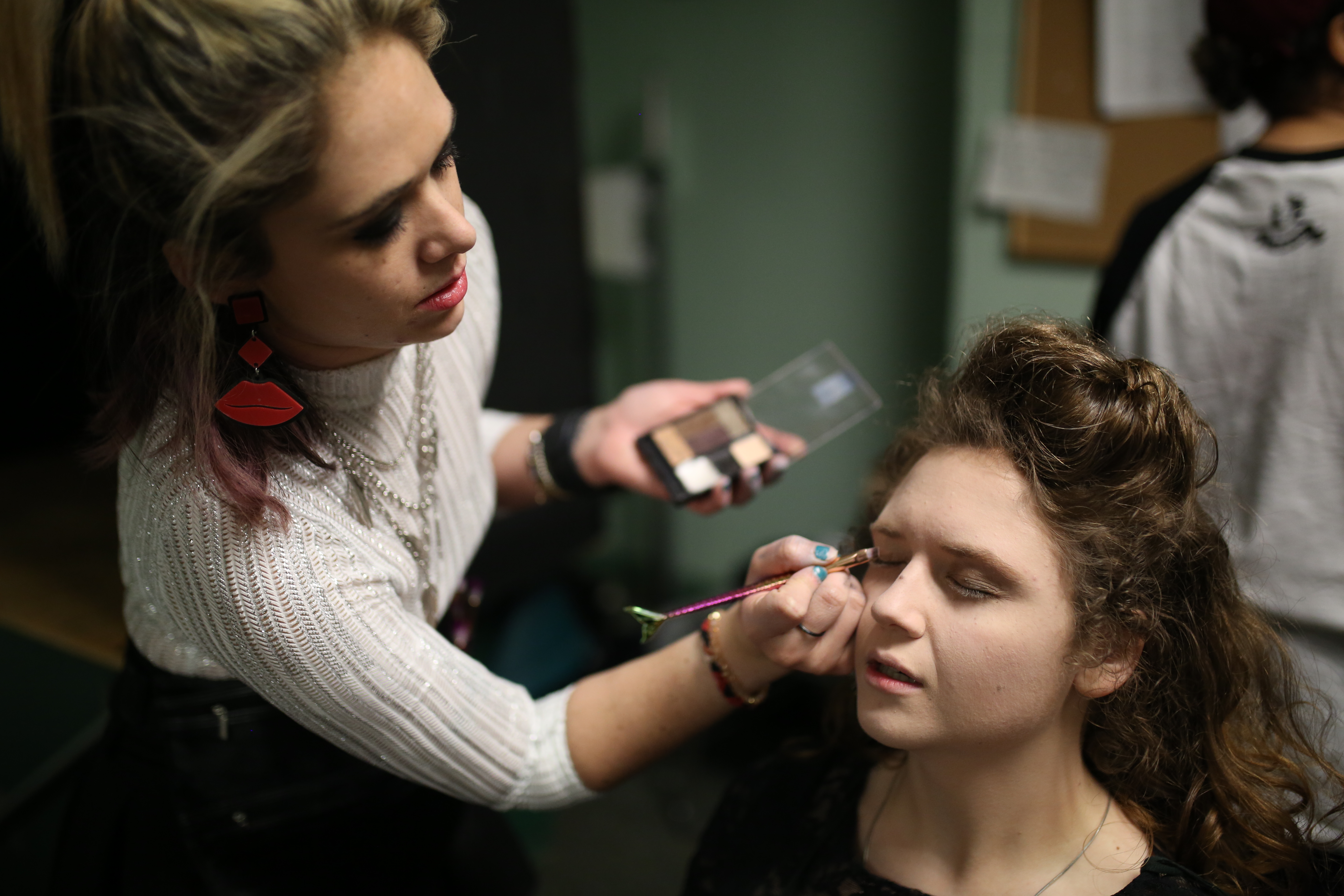 Sophomore Kit Keown sits in the makeup chair as stage manager Jace White helps her get into character.