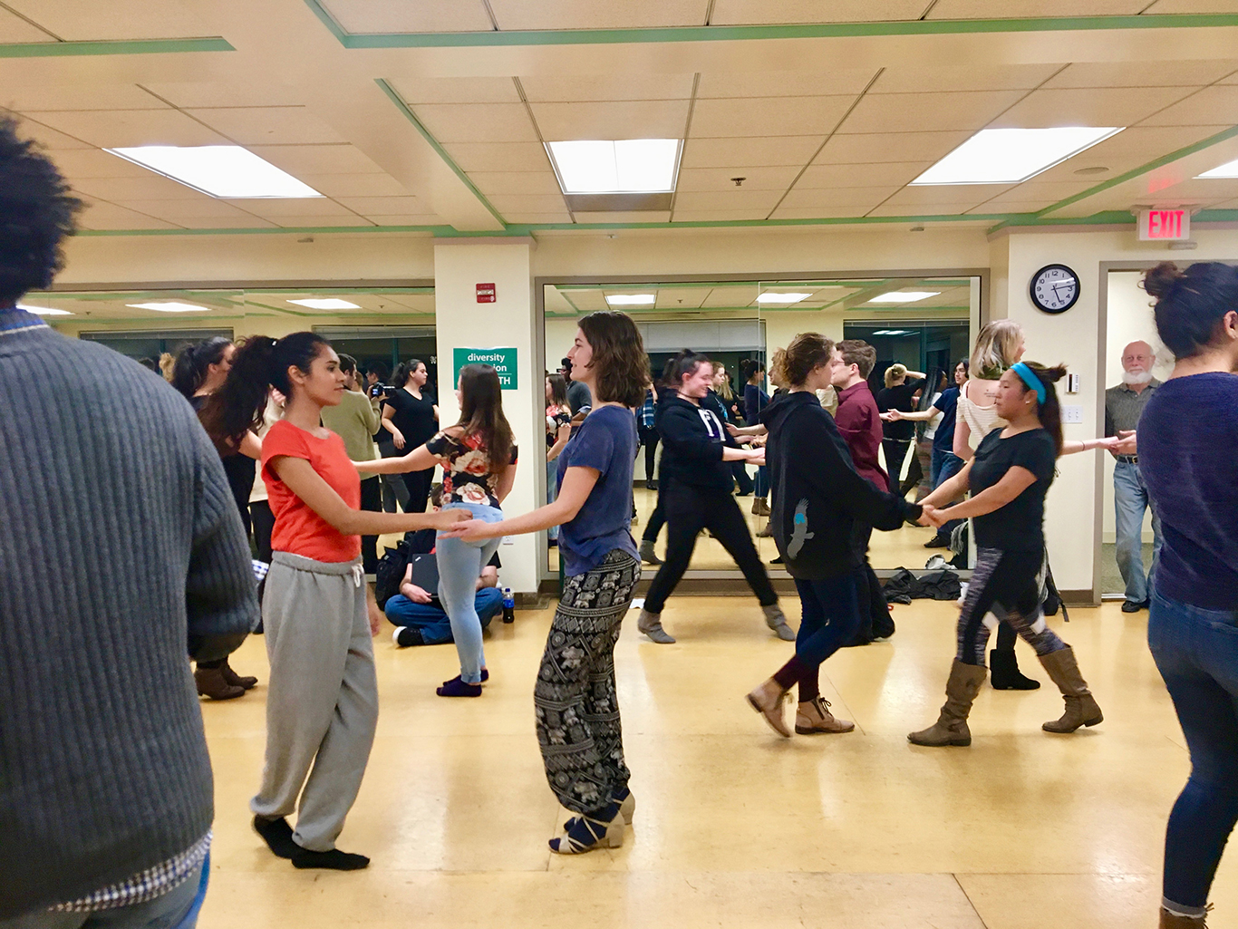 Students partner-dancing in swing dance class in dance studio.