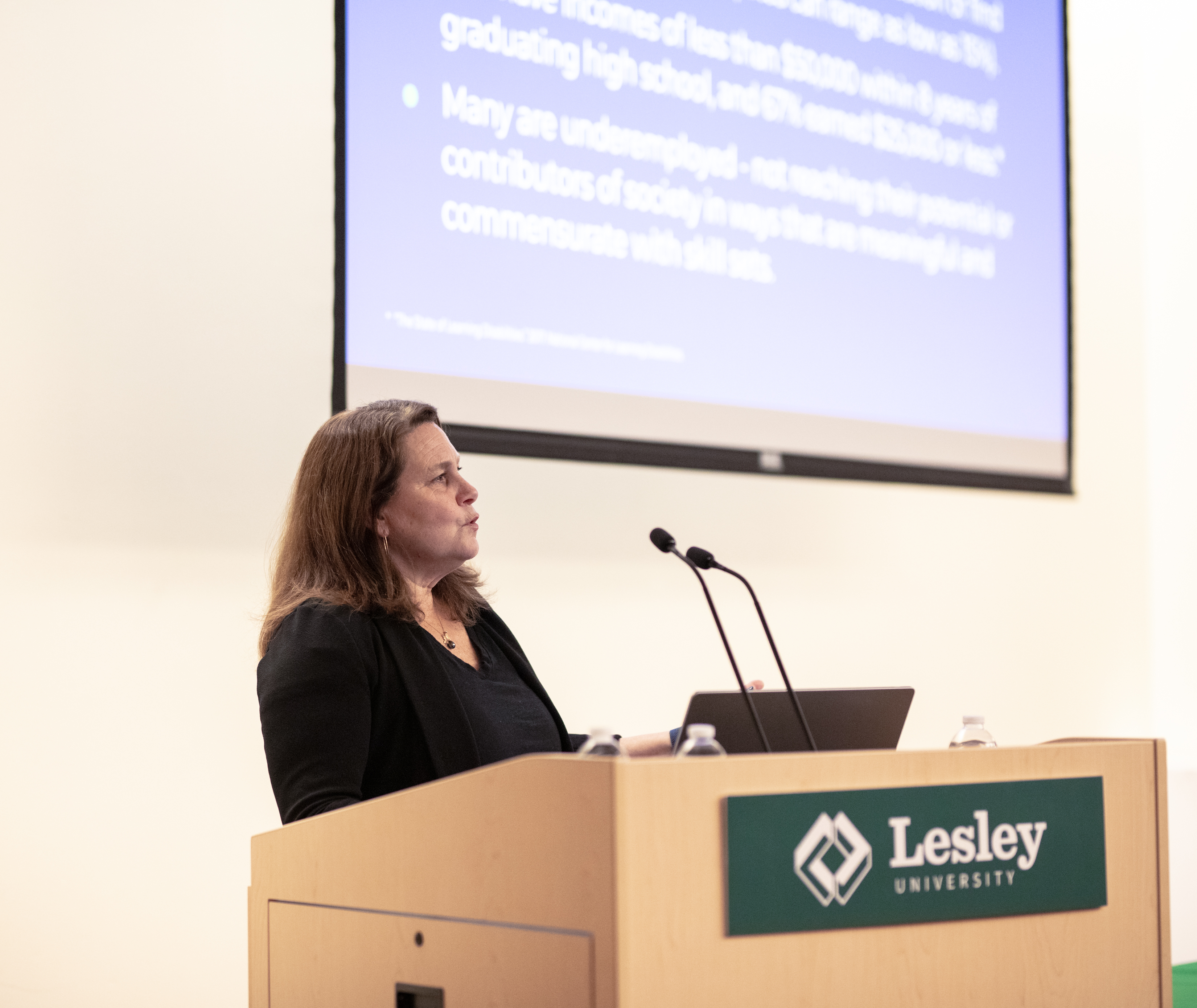 Carolyn Jeppsen at podium in front of slide show