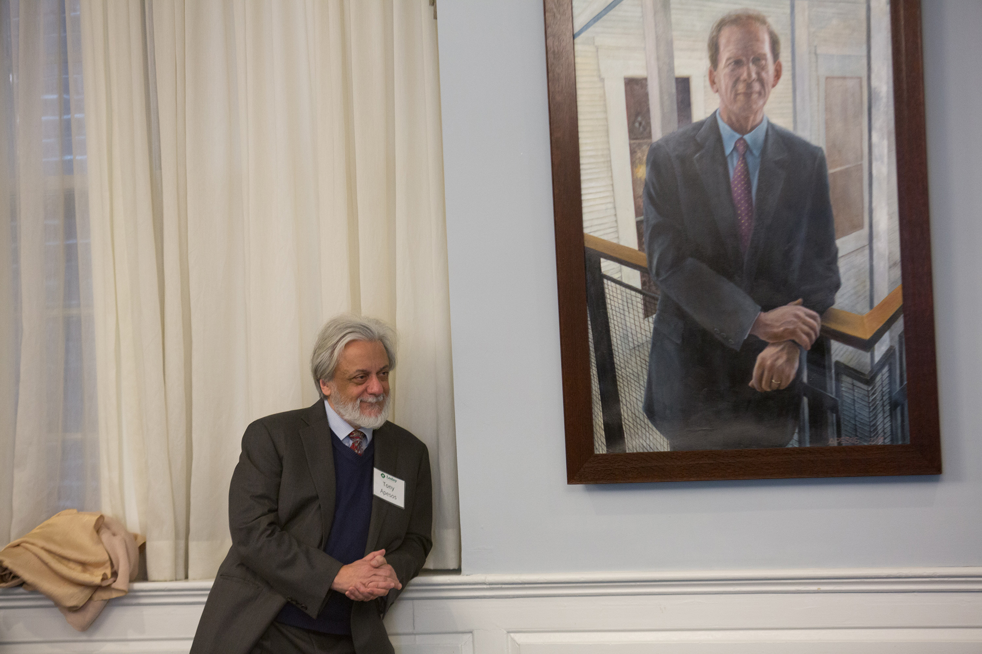 Tony Apesos leans against the Alumni Hall windowsill in the foreground of the portrait he painted of Joe Moore