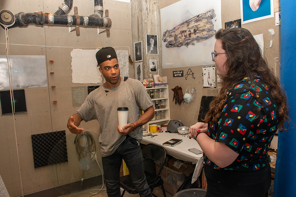 artist talking to student in small artist studio space