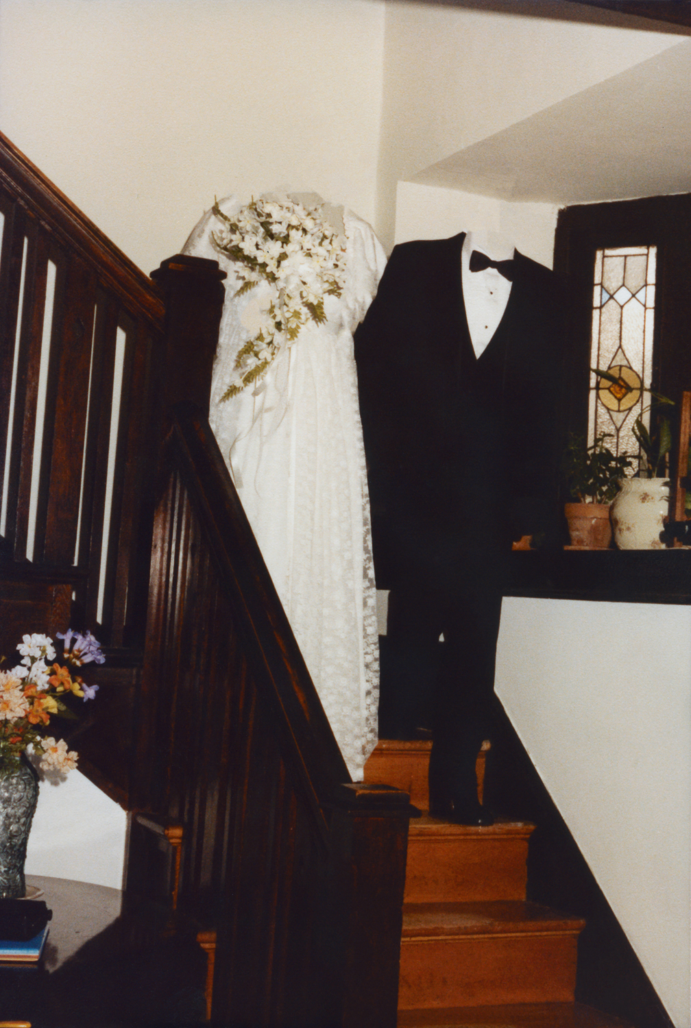 A bride and groom on stairs in a house with heads erased
