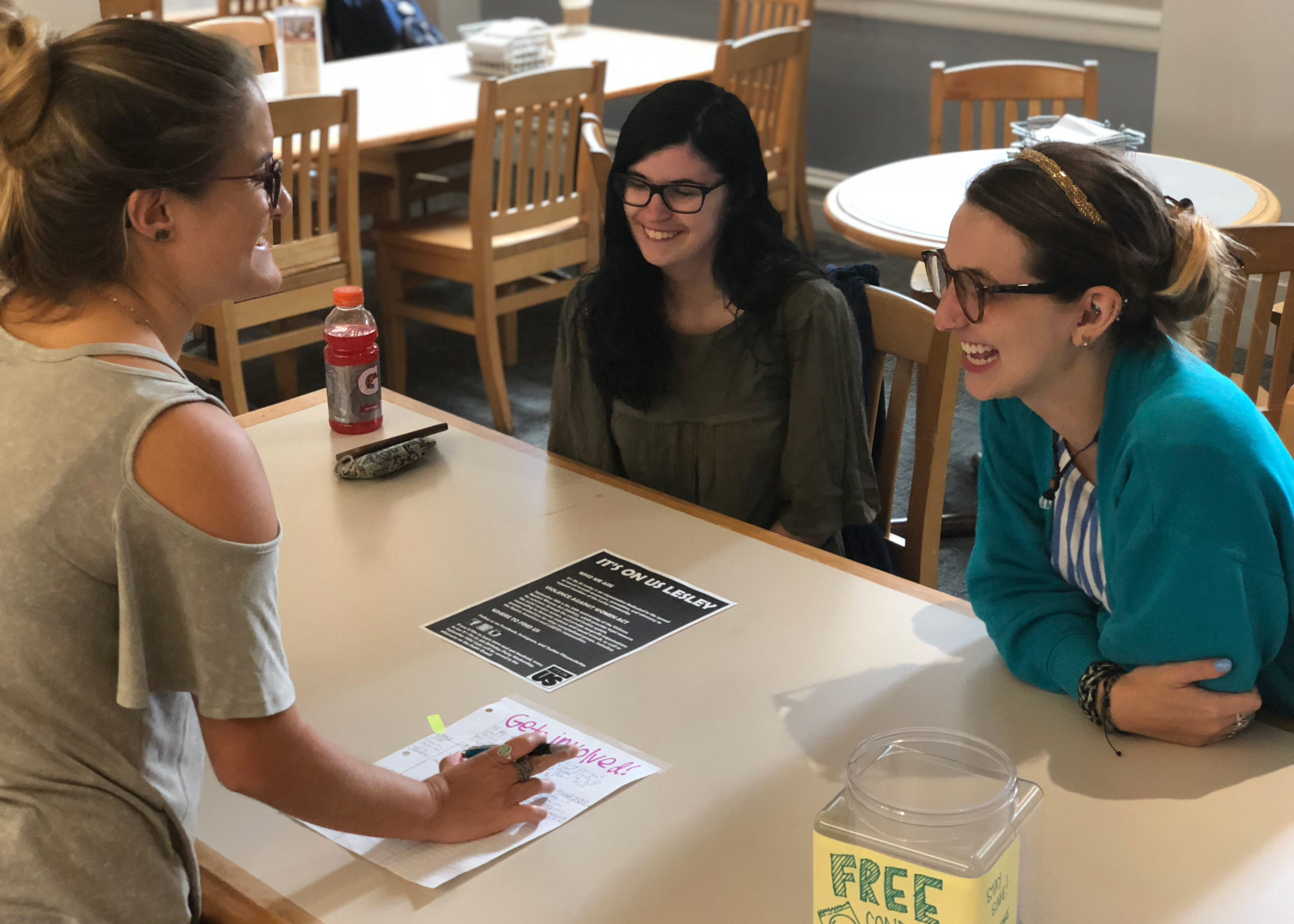 Three students are conversing at a table in White Hall.