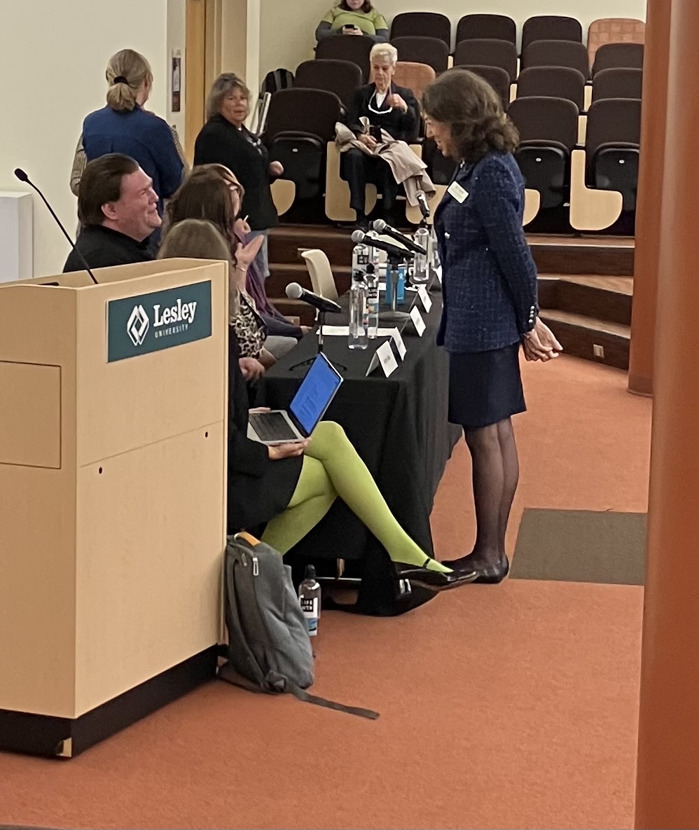 President Steinmayer speaks with panelists prior to UHall amnphitheater event, podium in foreground with Lesley logo