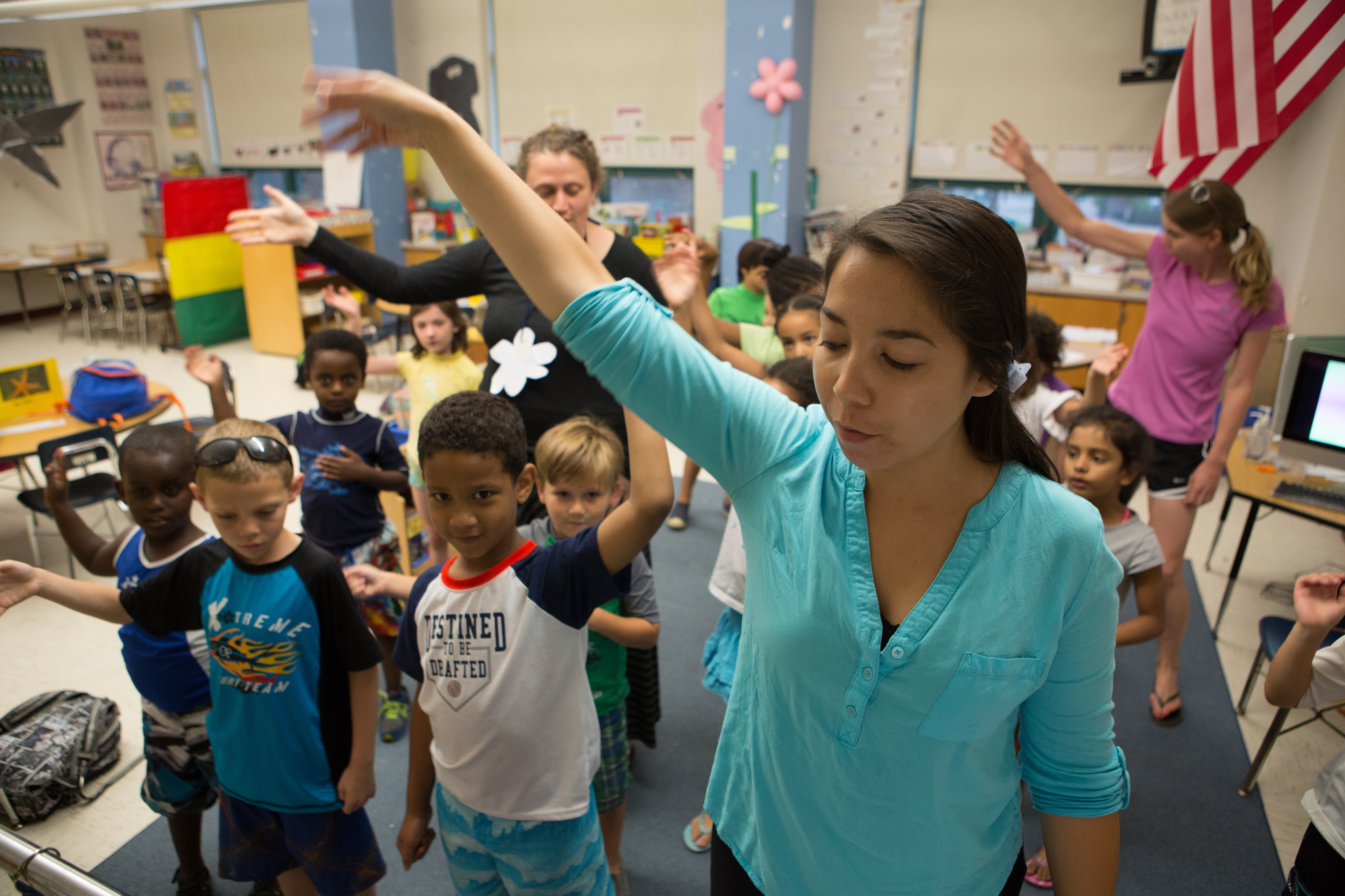 Teacher at the front of the classroom teaching a dance/movement step to students