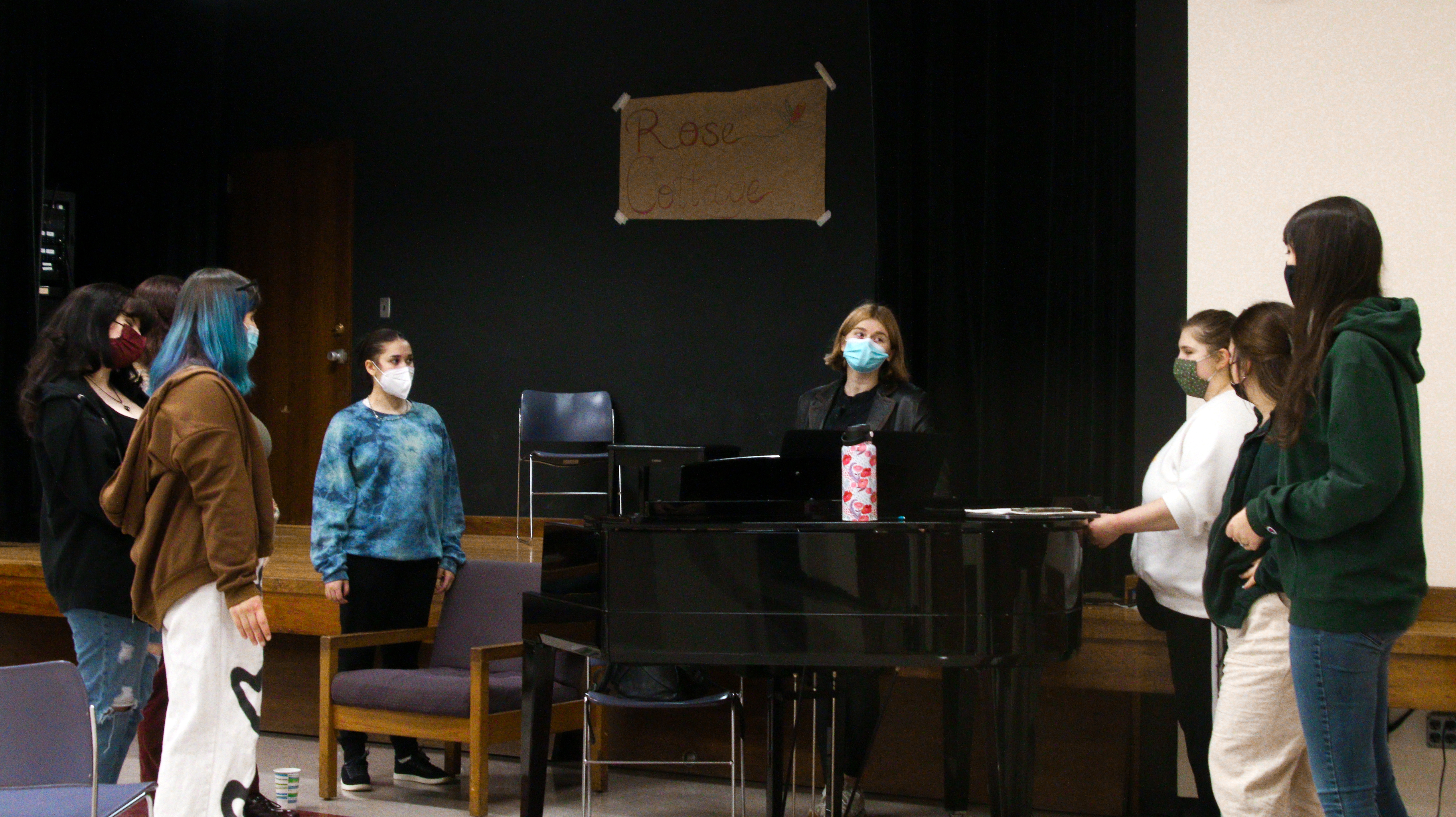students stand around a grand piano during cabaret rehearsal