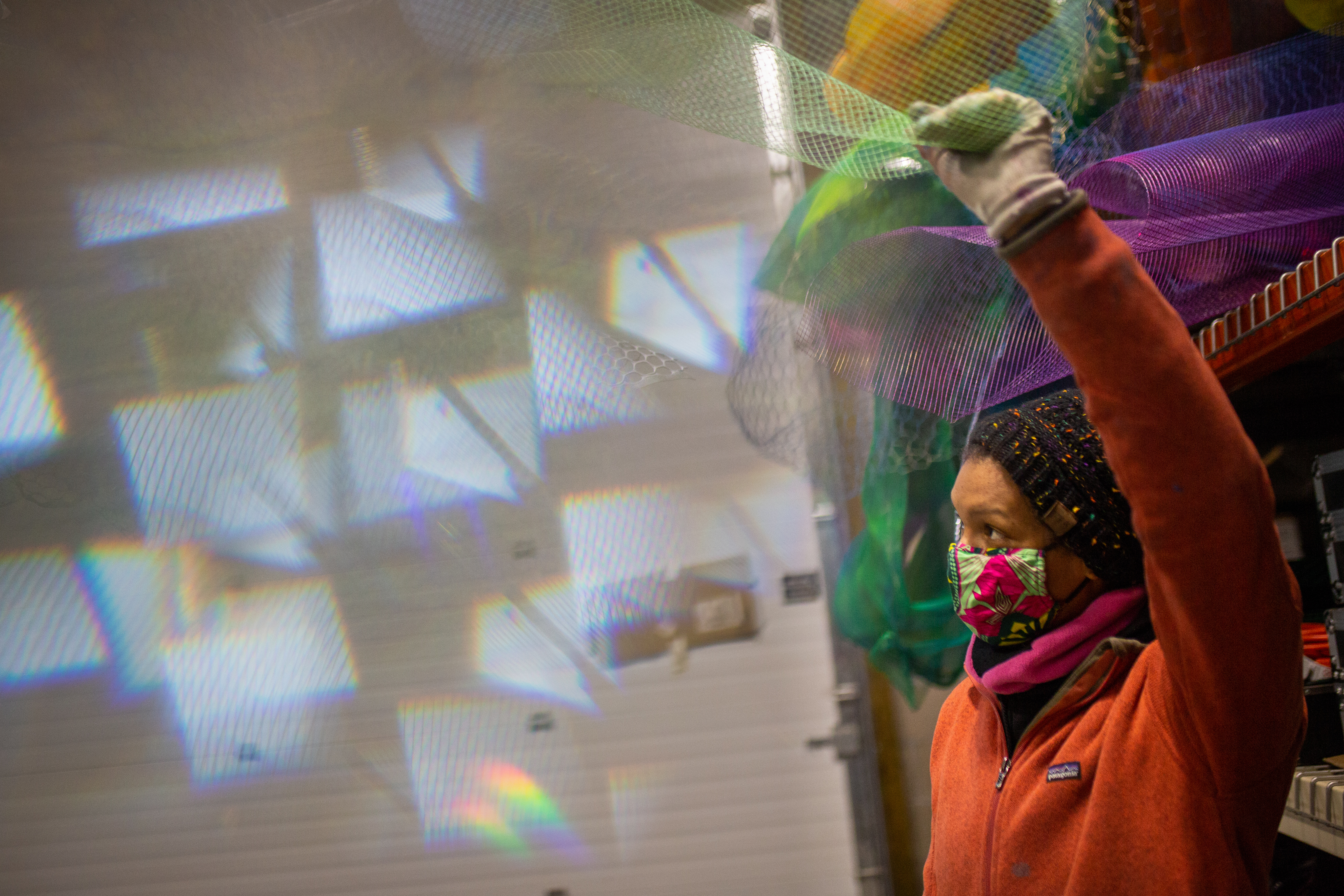 Cicely Carew holds up a piece of mesh and looks at the patterns it reflects on the wall.