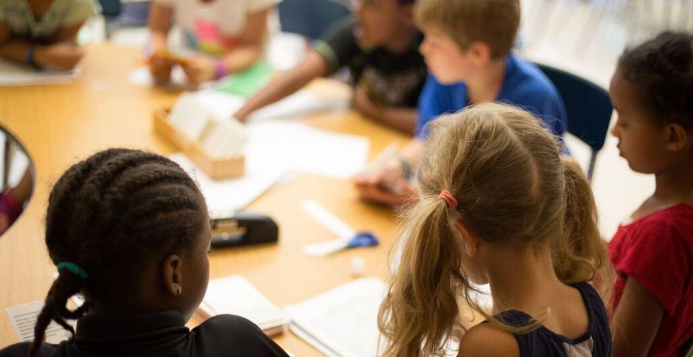 classroom students sit around the table doing schoolwork