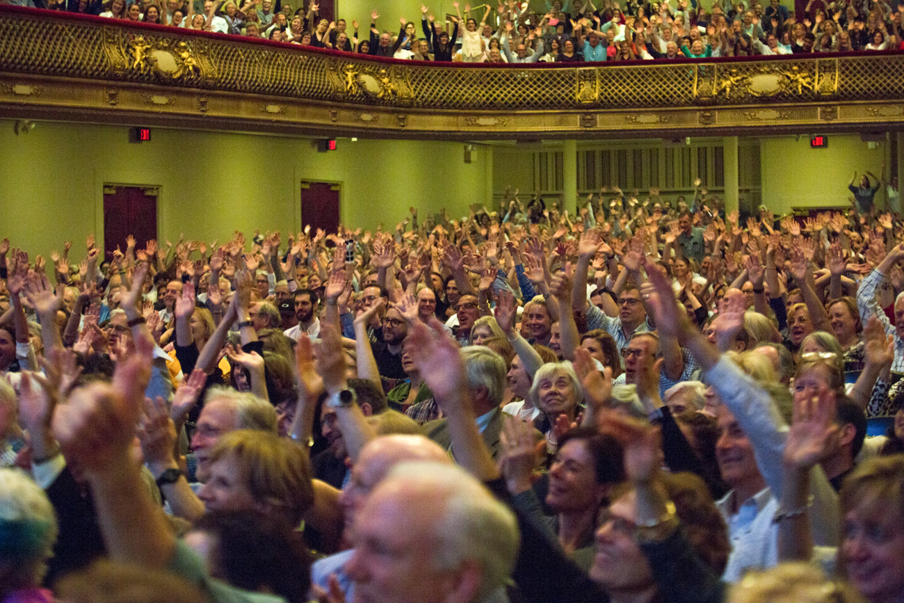 The large crowd at Boston Symphony Hall waves.