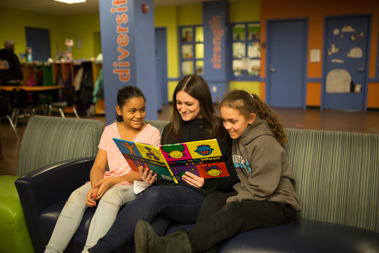 woman reading book to two children