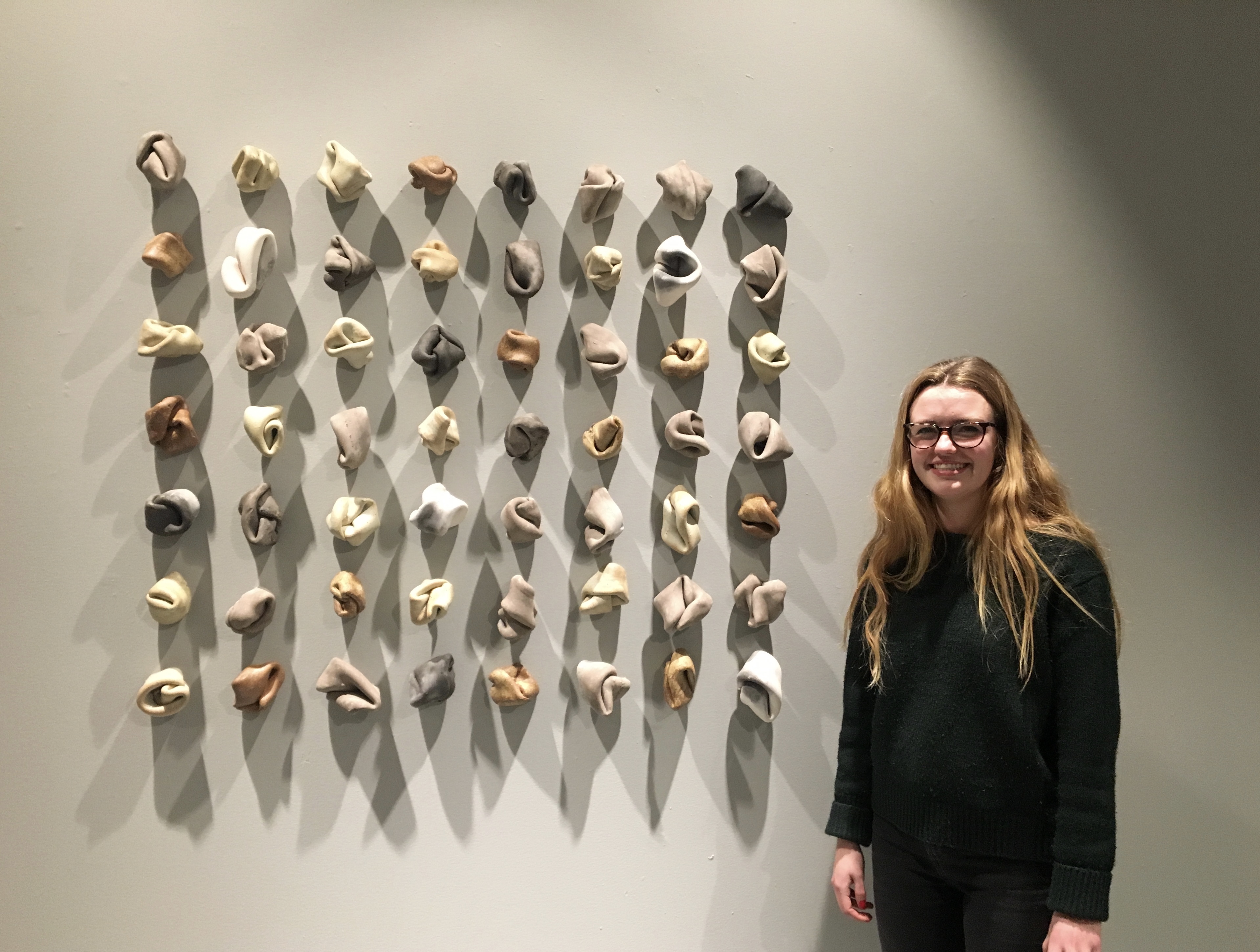student standing next to ceramic knots drilled to the wall