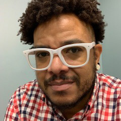 Headshot of Tre'Andre Valentine wearing white glasses and a red plaid shirt.