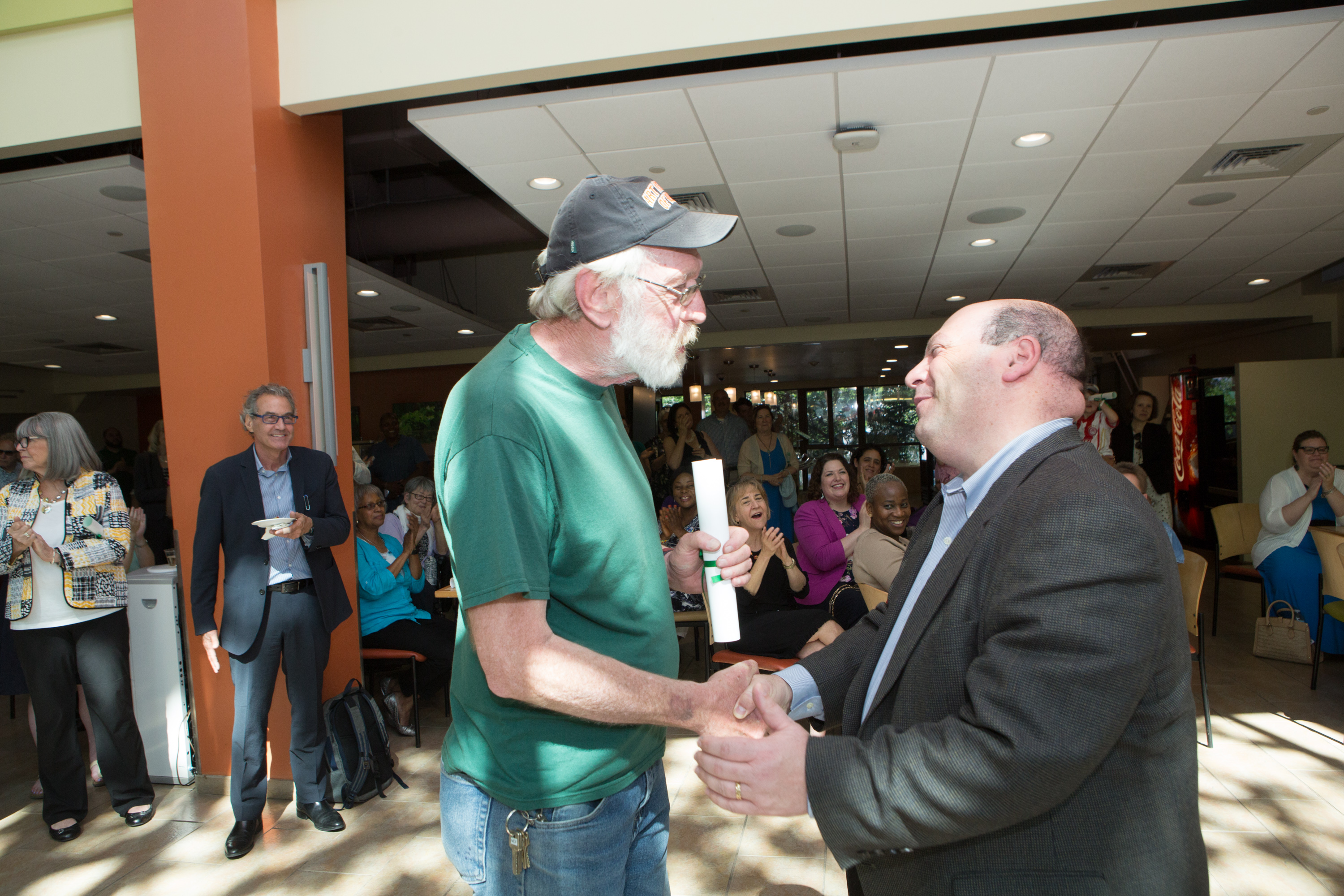 Retiring phones maven Matthew Scheppard, left, accepts congratulations from President Jeff Weiss at a party at the student center