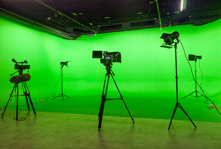 A photo of cameras on tripods in front of a green screen