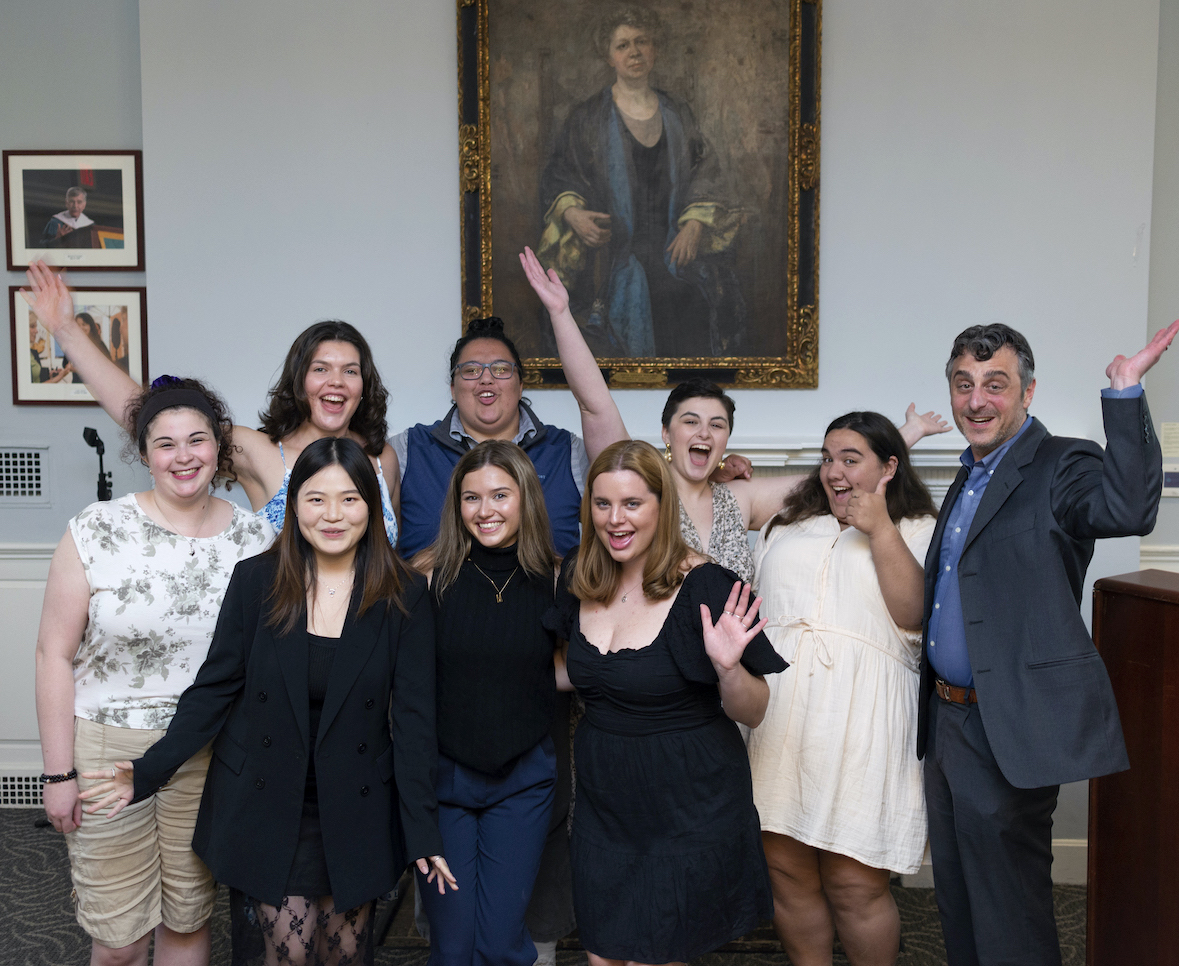 Group of honors students clowning for hte camera in front of portrait of Edith Lesley